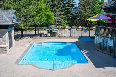 a small blue swimming pool with an umbrella at Sweet Retreat Ski-In Ski-Out - Pool & Hot Tub in Blue Mountains