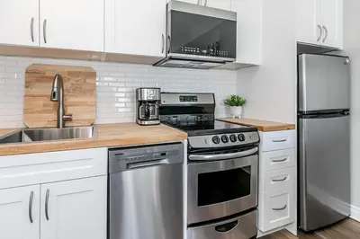 a kitchen with white cabinets and stainless steel appliances at Wanderer Way Loft Ski-In Ski-Out - Pool & Hot Tub in Blue Mountains
