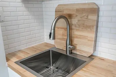 a kitchen counter with a sink and a wooden cutting board at Wanderer Way Loft Ski-In Ski-Out - Pool & Hot Tub in Blue Mountains