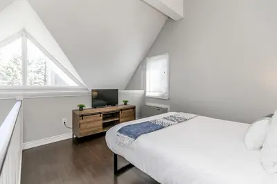 a white bedroom with a bed and a television at Wanderer Way Loft Ski-In Ski-Out - Pool & Hot Tub in Blue Mountains