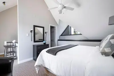 a bedroom with a white bed and a ceiling fan at Stay A While Ski-In-Out Hot Tub & Shuttle in Blue Mountains