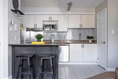 a kitchen with white cabinets and a counter with stools at Stay A While Ski-In-Out Hot Tub & Shuttle in Blue Mountains