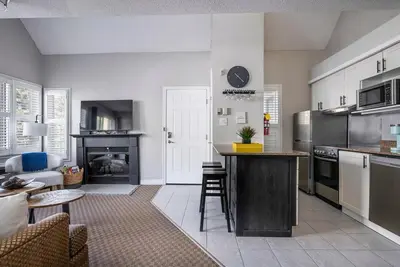 a kitchen with a counter and a living room at Stay A While Ski-In-Out Hot Tub & Shuttle in Blue Mountains