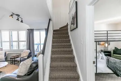 a staircase in a living room with a couch and a chair at Mountain Peaks Ski-In-Out Pool Shuttle in Blue Mountains