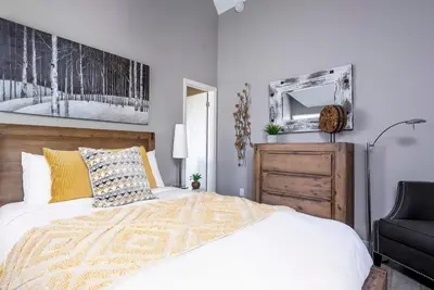 a bedroom with a bed and a chair and a mirror at Foxwood Retreat - Shuttle to Blue Pool & Hot Tub in Blue Mountains