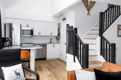 a kitchen with white cabinets and a staircase in a room at Northern Peaks Ski In-Out Hot Tub Shuttle Access in Blue Mountains