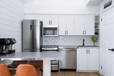 a kitchen with white cabinets and a stainless steel refrigerator at Northern Peaks Ski In-Out Hot Tub Shuttle Access in Blue Mountains