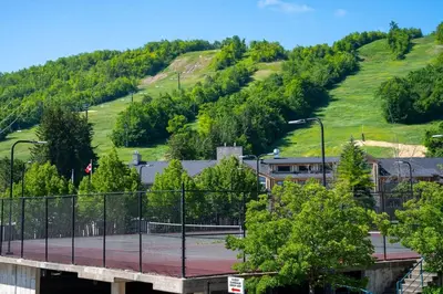 a tennis court in front of a hill at Mountainside Escape Ski-In-Out Pool Shuttle in Blue Mountains