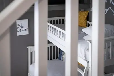 a room with two bunk beds and a staircase with a sign at Fox Ridge - Ski-In-Out Pool Hot Tub Shuttle in Blue Mountains