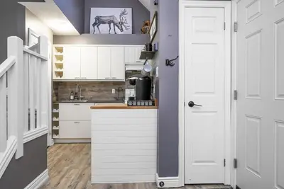 a kitchen with white cabinets and a horse painting on the wall at Fox Ridge - Ski-In-Out Pool Hot Tub Shuttle in Blue Mountains