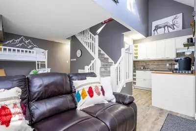 a living room with a leather couch and a kitchen at Fox Ridge - Ski-In-Out Pool Hot Tub Shuttle in Blue Mountains