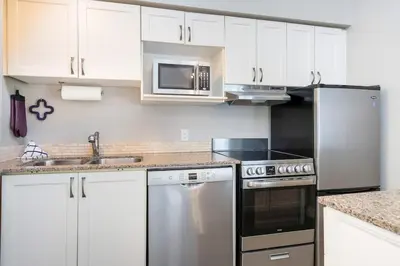 a kitchen with white cabinets and stainless steel appliances at Whispering Pines - Ski-In-Ou Pool Shuttle in Blue Mountains