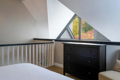 a attic bedroom with a bed and a window at Whispering Pines - Ski-In-Ou Pool Shuttle in Blue Mountains