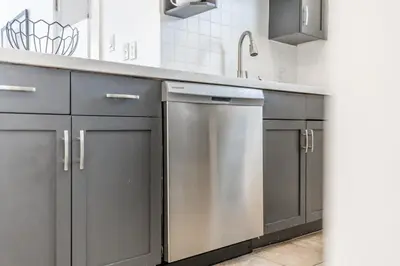 a kitchen with gray cabinets and a stainless steel dishwasher at Rivergrass Oasis Across from Blue Mtn Hot Tub in Blue Mountains