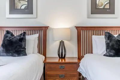 a bedroom with two beds and a table with a lamp at Rivergrass Oasis Across from Blue Mtn Hot Tub in Blue Mountains