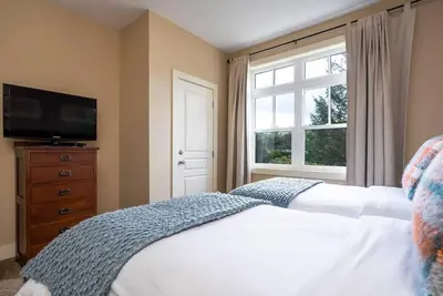 a bedroom with a bed and a tv and a window at Hickory Ridge Across Blue Mtn Hot Tub Shuttle in Blue Mountains