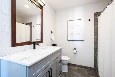 a white bathroom with a sink and a toilet at Three Suns Across Blue Mtn Hot Tub & Shuttle in Blue Mountains