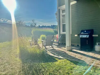 a patio with chairs and a grill next to a house at Three Suns Across Blue Mtn Hot Tub & Shuttle in Blue Mountains