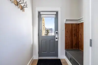 a hallway with a gray door and a window at Three Suns Across Blue Mtn Hot Tub & Shuttle in Blue Mountains