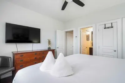 a bedroom with a white bed with a flat screen tv at The Blue - Walk to the Village Shuttle & Hot Tub in Blue Mountains