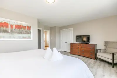 a white bedroom with a large bed and a couch at Sunny Days - Steps to Blue Mtn - Hot Tub & Shuttle in Blue Mountains