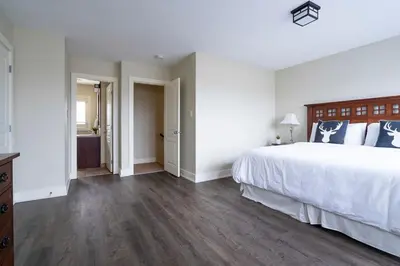a white bedroom with a large bed and wooden floors at Bears Den - Hot Tub - Ski Views - Walk to Village in Blue Mountains