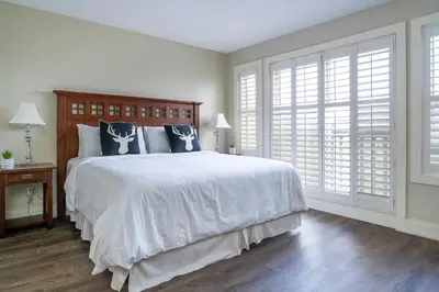 a white bedroom with a large bed and windows at Bears Den - Hot Tub - Ski Views - Walk to Village in Blue Mountains