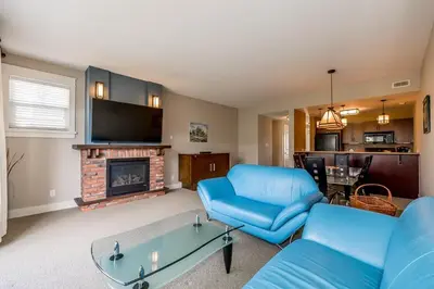 a living room with a blue couch and a fireplace at Raccoon Ridge - Village Walk - Hot Tub - Shuttle in Blue Mountains