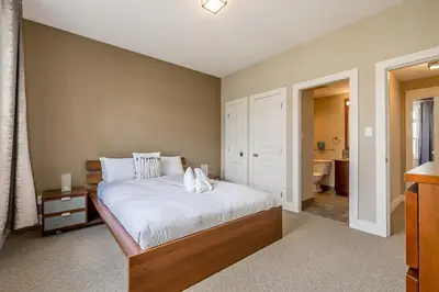 a bedroom with a large bed and a bathroom at Raccoon Ridge - Village Walk - Hot Tub - Shuttle in Blue Mountains