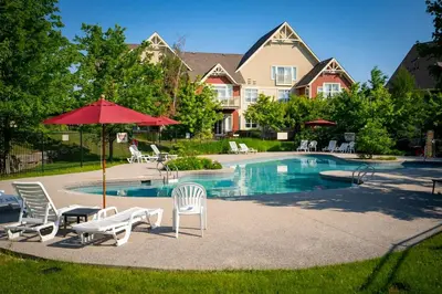 a pool with chairs and umbrellas in front of a house at Raccoon Ridge - Village Walk - Hot Tub - Shuttle in Blue Mountains