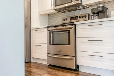 a kitchen with a stainless steel stove and white cabinets at Hip Hideaway - Family Fun Walk to the Village in Blue Mountains