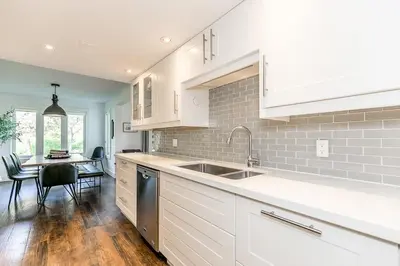 a kitchen with white cabinets and a sink and a table at Hip Hideaway - Family Fun Walk to the Village in Blue Mountains