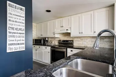 a kitchen with white cabinets and a stainless steel sink at Sierra Views - Steps to Blue Mountain Village in Blue Mountains