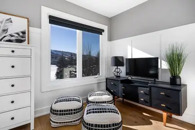 a living room with a tv and two stools at View to Blue - Walk to the Village Mountain Views in Blue Mountains