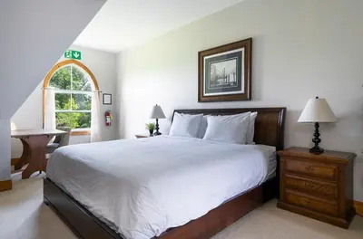 a bedroom with a large bed and a window at Still Winds - Private Patio - Shuttle to Blue in Blue Mountains