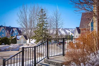 a black rail fence in a snow covered neighborhood at Snowy Mountain Summit & Sol - Shuttle - Patio in Blue Mountains