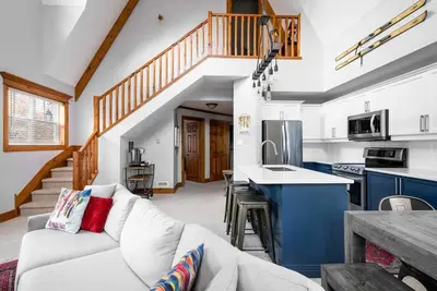 a living room with a white couch and a kitchen at Lookout Lodge - Private Patio - Shuttle to Blue in Blue Mountains
