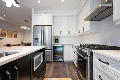 a kitchen with white cabinets and a stainless steel refrigerator at Blue Mountain Townhome - Patio Shuttle Trails in Blue Mountains