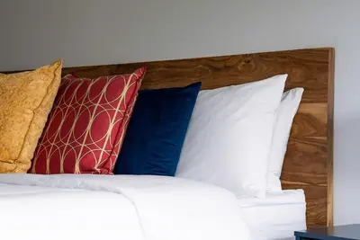 a pile of pillows on a bed with a wooden headboard at Blue Mountain Townhome - Patio Shuttle Trails in Blue Mountains