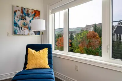 a blue chair with a yellow pillow in a room with a window at Blue Mountain Townhome - Patio Shuttle Trails in Blue Mountains