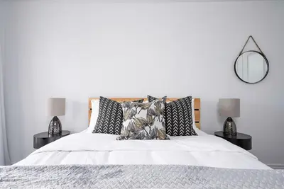 a bedroom with a white bed with pillows and a mirror at Blue Mountain Townhome - Patio Shuttle Trails in Blue Mountains
