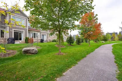 a house with a tree in the yard at Blue Mountain Townhome - Patio Shuttle Trails in Blue Mountains