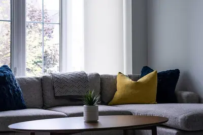 a living room with a couch with pillows and a table at Blue Mountain Townhome - Patio Shuttle Trails in Blue Mountains