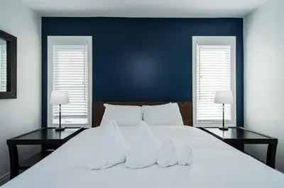 a bedroom with a large white bed with two windows at Luxury Mountain Townhome - Shuttle Patio & Trails in Blue Mountains