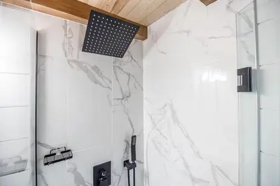 a bathroom with white marble walls and a shower at The Hideaway - Tiny House in Flesherton