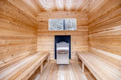 a wooden sauna with two benches and a window at The Hideaway - Tiny House in Flesherton
