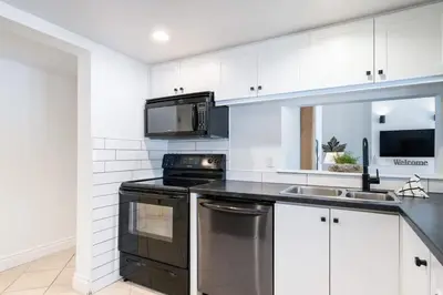 a kitchen with white cabinets and a stove and a microwave at The Mountain House - Walk to the Village in Blue Mountains