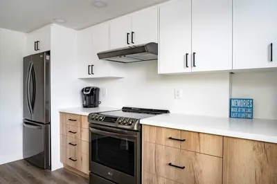 a kitchen with white cabinets and a black stove top oven at Apres-Blu - Walk to theVillage - Sleeps 7 in Blue Mountains