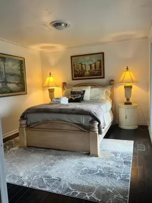 a bedroom with a bed with two lamps and a rug at Grimsby Lakeside Vacation Home in Grimsby