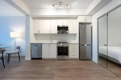a kitchen with white cabinets and a bed in a room at RivetStays - The Westmounts in Toronto